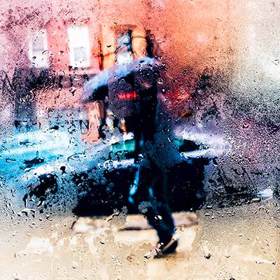 Mensch mit Regenschirm durch beschlagene Glasscheibe