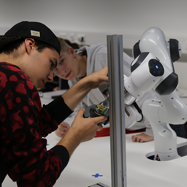 Student arbeitet an einem Roboter in der Roboterfabrik